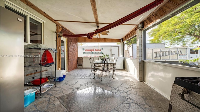 sunroom with lofted ceiling with beams and a ceiling fan