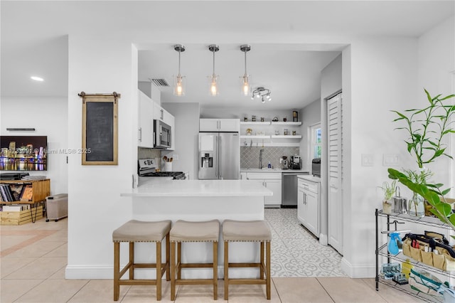 kitchen featuring stainless steel appliances, white cabinetry, a breakfast bar, and decorative light fixtures