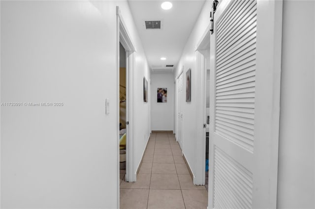 hallway featuring light tile patterned floors and a barn door