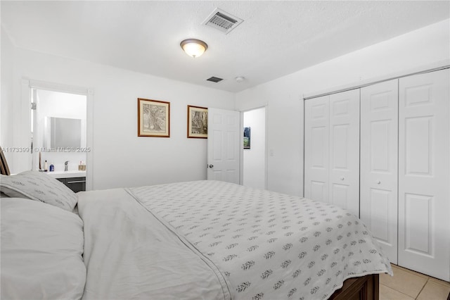 tiled bedroom featuring a textured ceiling and a closet