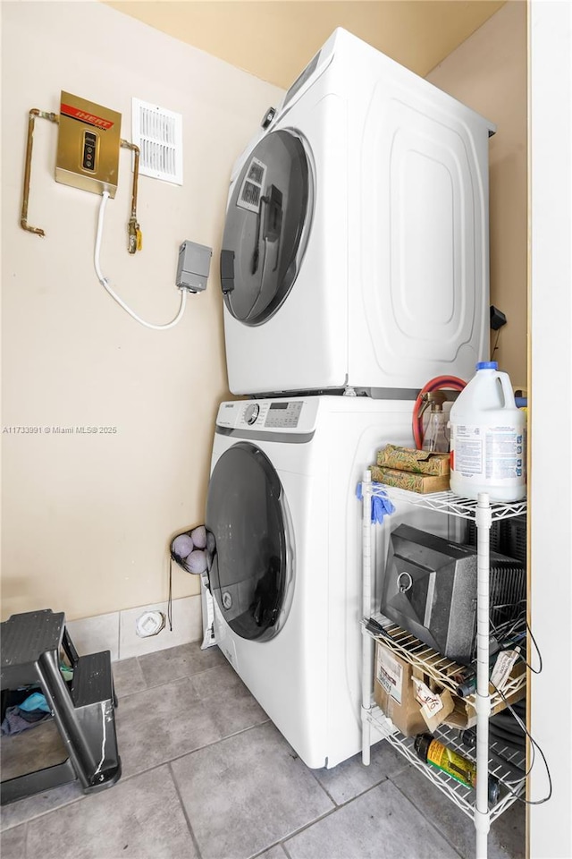 clothes washing area featuring stacked washer / drying machine and light tile patterned floors