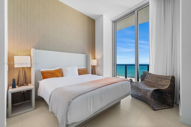 bedroom featuring a water view, expansive windows, access to exterior, and light tile patterned floors