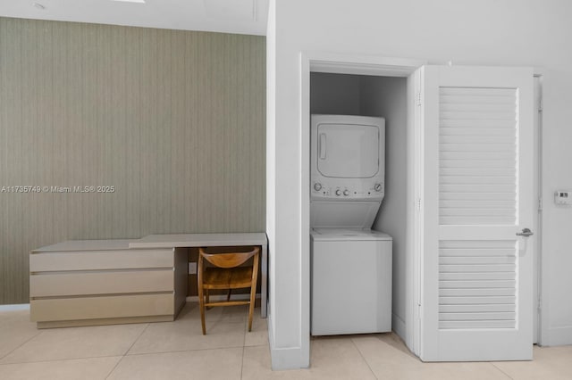 laundry area with stacked washing maching and dryer and light tile patterned floors