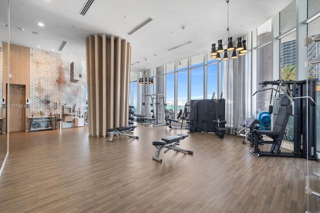 gym with floor to ceiling windows, hardwood / wood-style floors, a high ceiling, and a notable chandelier