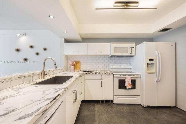 kitchen featuring sink, light stone counters, white cabinetry, white appliances, and decorative backsplash