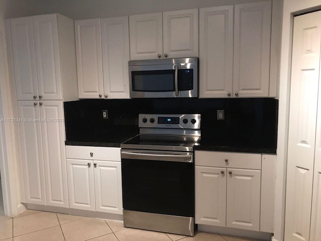 kitchen with stainless steel appliances, light tile patterned floors, and white cabinets