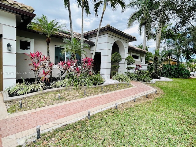 exterior space featuring stucco siding, a lawn, and a tiled roof