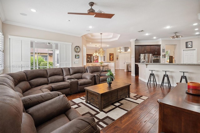 living room featuring dark wood-style flooring, crown molding, and ceiling fan with notable chandelier