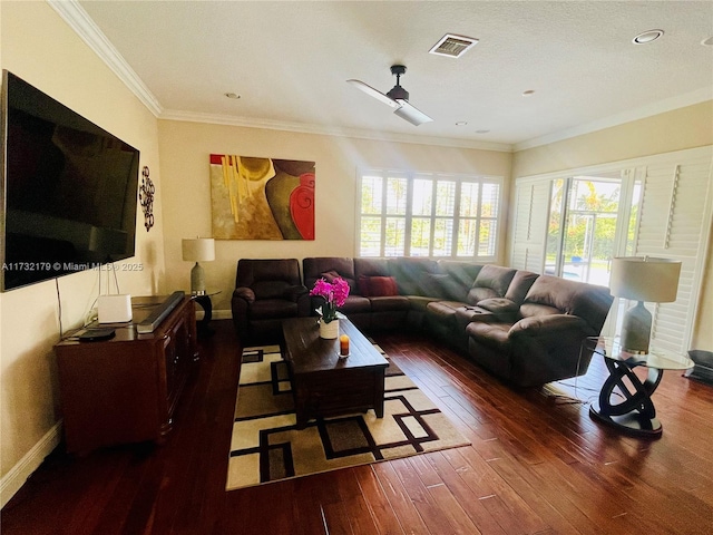 living area with dark wood-style flooring, crown molding, visible vents, a ceiling fan, and baseboards