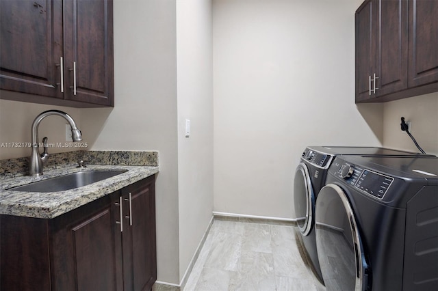 laundry area featuring cabinet space, baseboards, a sink, and independent washer and dryer