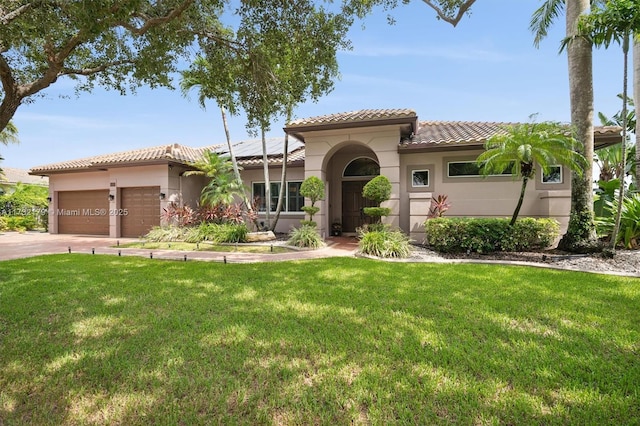 mediterranean / spanish-style house featuring a garage, a tiled roof, a front lawn, and stucco siding