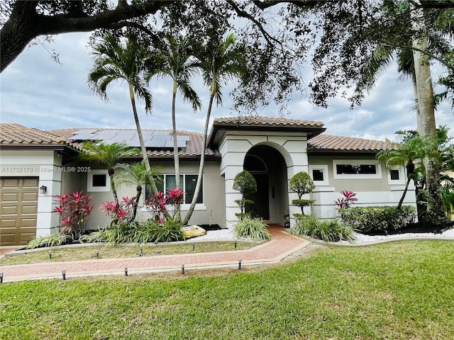 mediterranean / spanish house featuring a garage, a front yard, a tile roof, and stucco siding