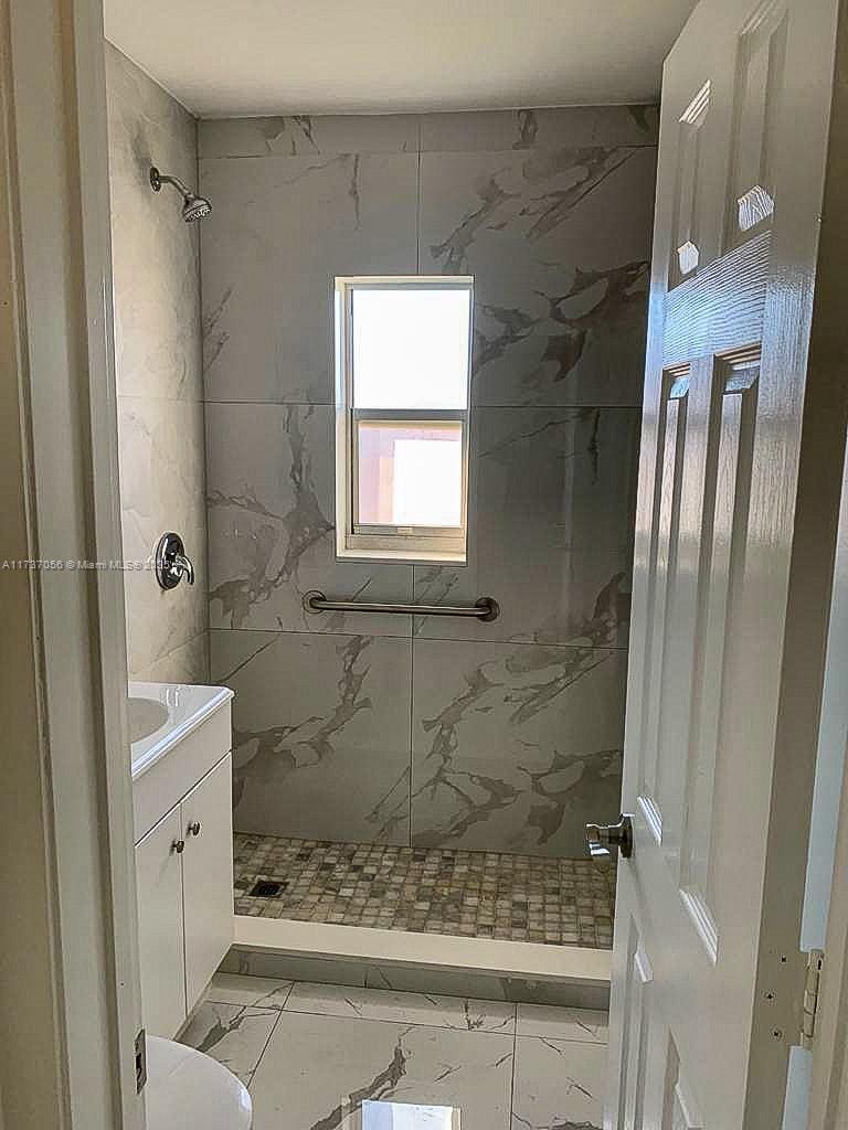 bathroom with vanity, toilet, and tiled shower