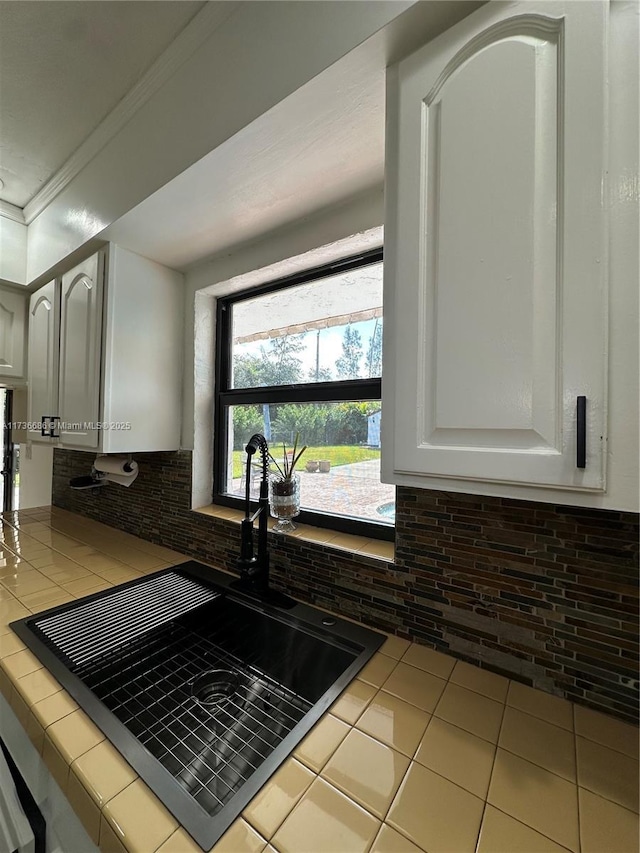 kitchen featuring light tile patterned floors, backsplash, ornamental molding, white cabinets, and tile countertops