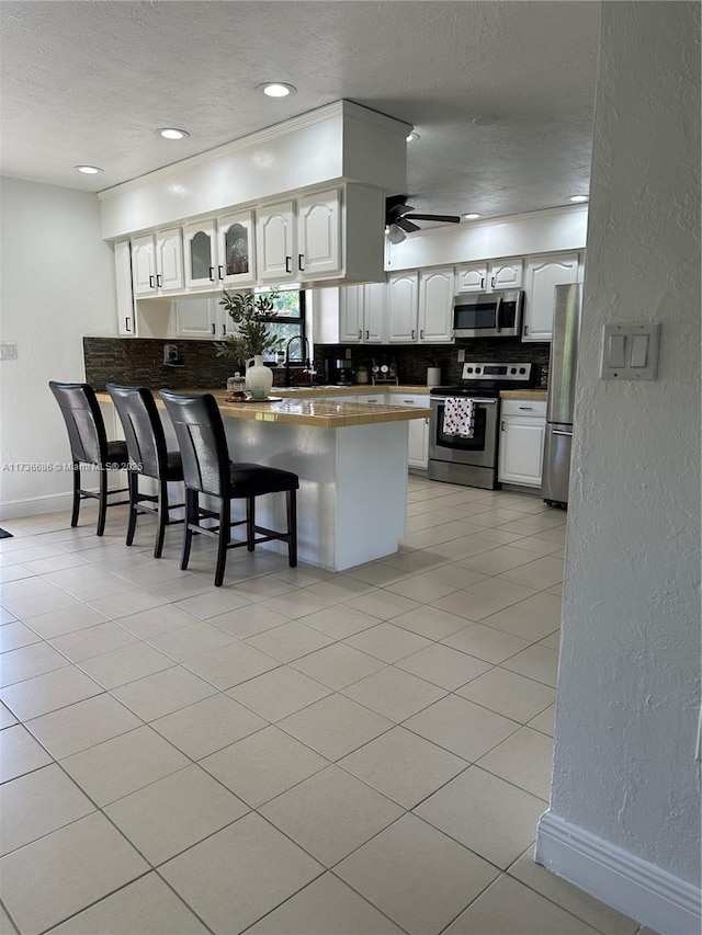 kitchen featuring a breakfast bar area, stainless steel appliances, kitchen peninsula, and white cabinets