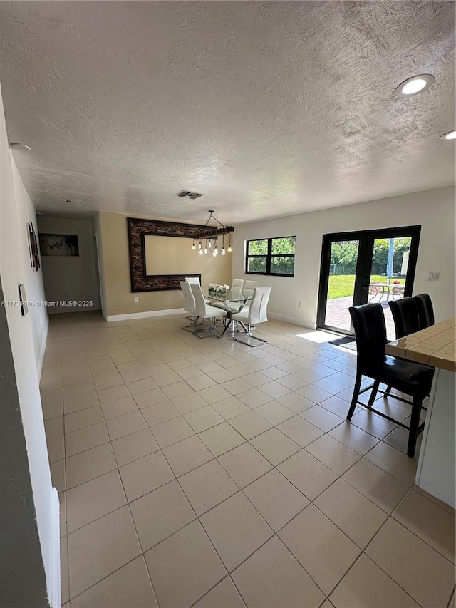 unfurnished living room featuring french doors, a textured ceiling, and light tile patterned floors