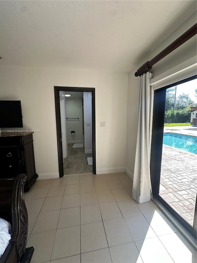 unfurnished bedroom featuring access to outside, a textured ceiling, and light tile patterned flooring