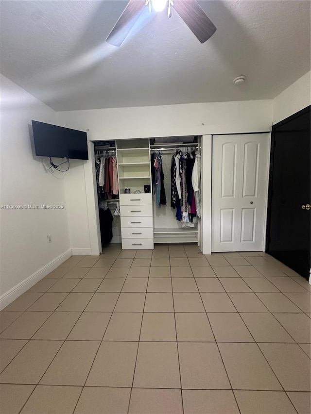 unfurnished bedroom with light tile patterned floors, a closet, a textured ceiling, and ceiling fan