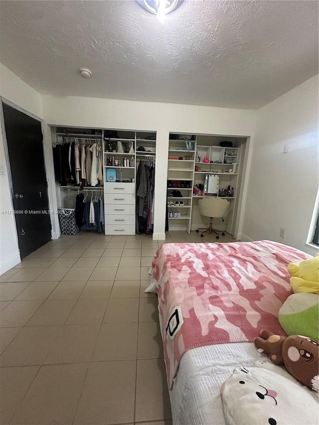 bedroom featuring two closets, tile patterned floors, and a textured ceiling