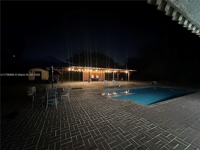 pool at night featuring a patio area