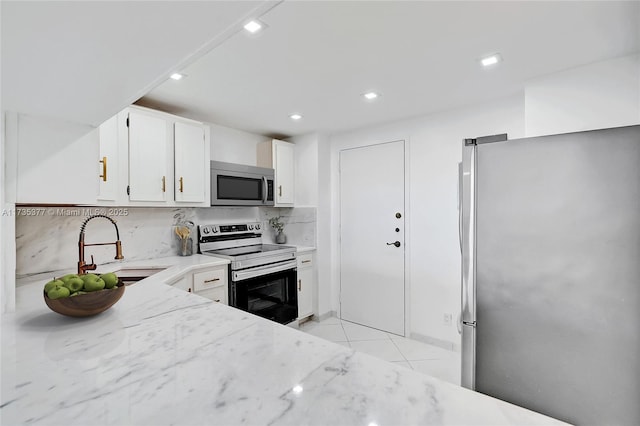 kitchen with sink, white cabinets, decorative backsplash, stainless steel appliances, and light stone countertops