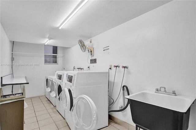 clothes washing area with sink, light tile patterned floors, and washer and dryer