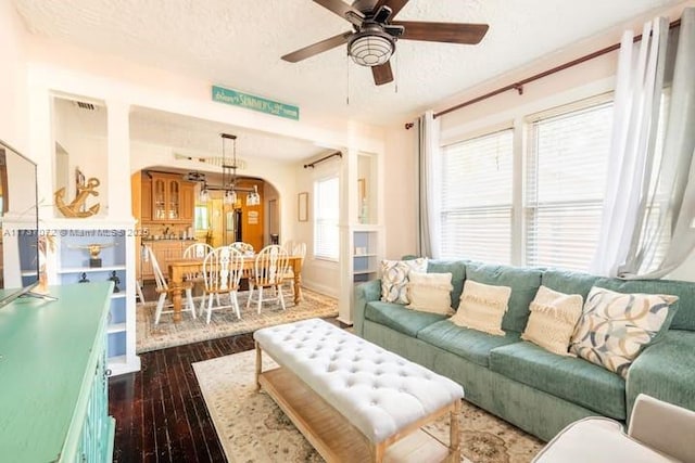 living room featuring ceiling fan, dark wood-type flooring, and a textured ceiling