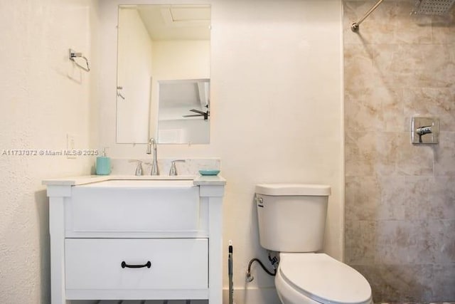 bathroom featuring vanity, tiled shower, and toilet