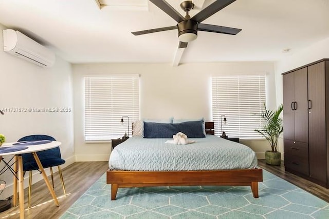 bedroom with a wall mounted air conditioner, hardwood / wood-style flooring, and ceiling fan