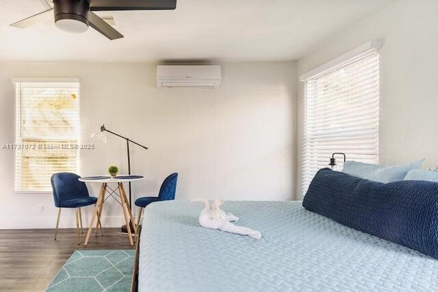 bedroom featuring hardwood / wood-style flooring, a wall unit AC, and ceiling fan