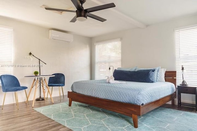 bedroom with ceiling fan, beam ceiling, wood-type flooring, and a wall mounted AC