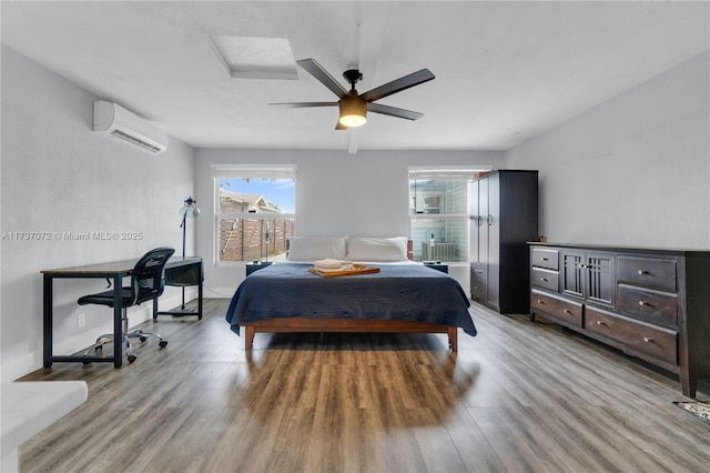 bedroom with a wall mounted AC, light wood finished floors, and ceiling fan