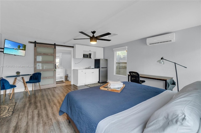 bedroom featuring a sink, wood finished floors, ceiling fan, a wall unit AC, and freestanding refrigerator