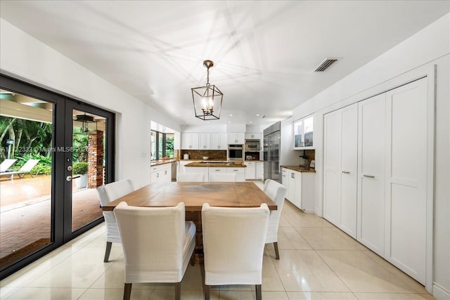 tiled dining area with an inviting chandelier and french doors