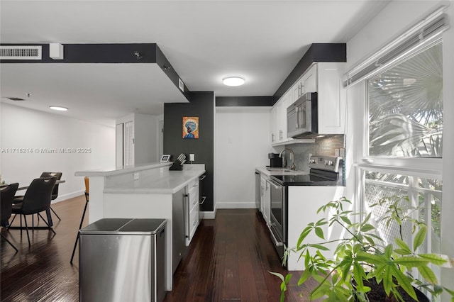 kitchen with tasteful backsplash, white cabinetry, sink, kitchen peninsula, and stainless steel appliances