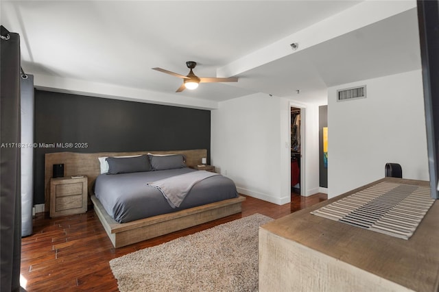 bedroom featuring dark hardwood / wood-style flooring, a walk in closet, and ceiling fan