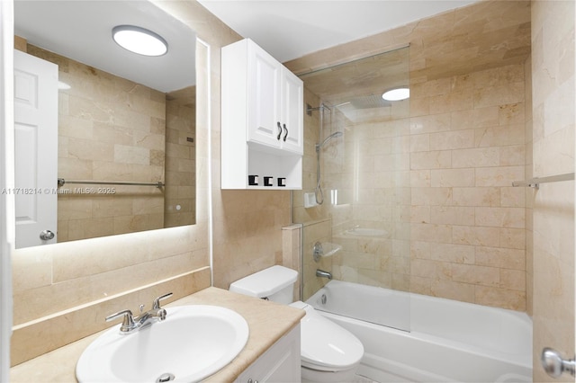 full bathroom featuring tile walls, decorative backsplash, tiled shower / bath combo, vanity, and toilet