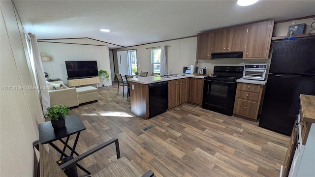 kitchen with lofted ceiling, sink, dark wood-type flooring, black appliances, and kitchen peninsula