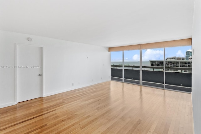 unfurnished room featuring wood-type flooring, expansive windows, and a water view