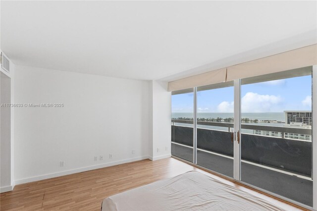 empty room featuring a water view and hardwood / wood-style flooring