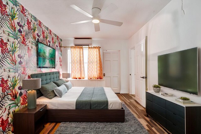 bedroom featuring ceiling fan, a wall mounted AC, and hardwood / wood-style floors