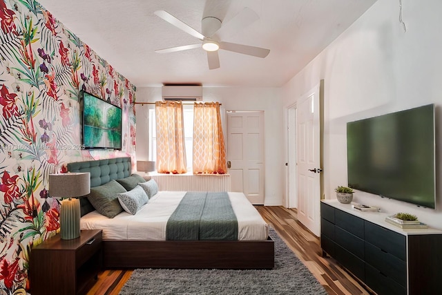 bedroom with a ceiling fan, wood finished floors, and a wall mounted AC