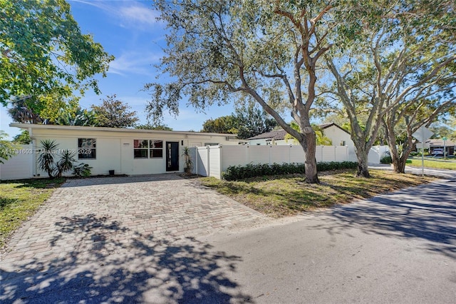 single story home featuring a gate, fence, and stucco siding