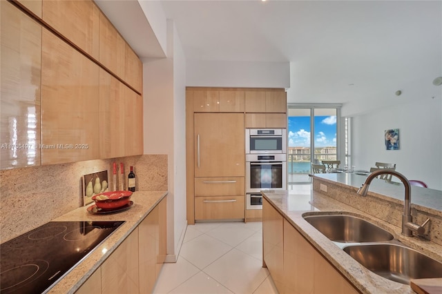 50 S Pointe Dr Unit 1704, Miami Beach, FL 33139 - kitchen with black electric stovetop, modern cabinets, light brown cabinetry, and a wall of windows