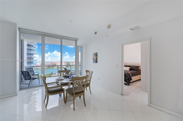 tiled dining room featuring a water view and floor to ceiling windows