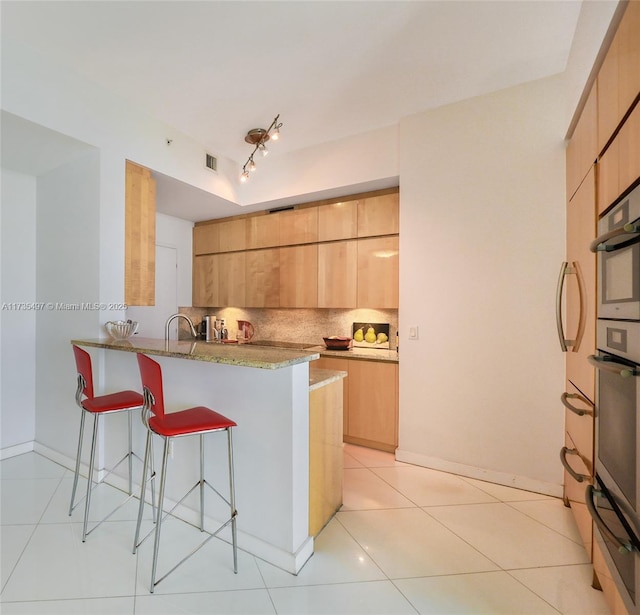 50 S Pointe Dr Unit 1704, Miami Beach, FL 33139 - kitchen featuring a breakfast bar area, a warming drawer, decorative backsplash, modern cabinets, and a peninsula