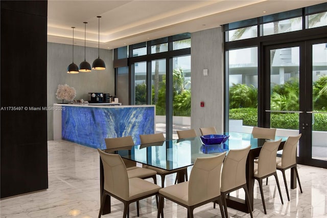 dining area with a tray ceiling, a wealth of natural light, floor to ceiling windows, and french doors