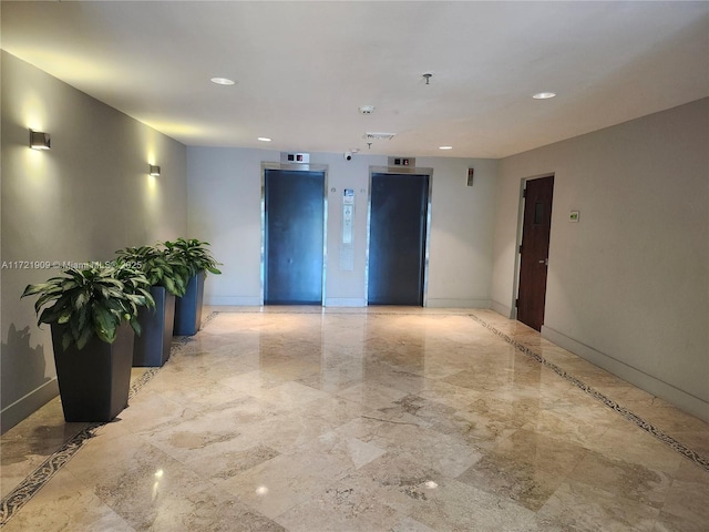 empty room with marble finish floor, baseboards, and elevator