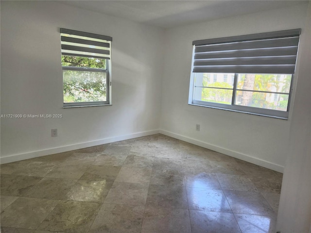unfurnished room featuring baseboards and stone finish flooring