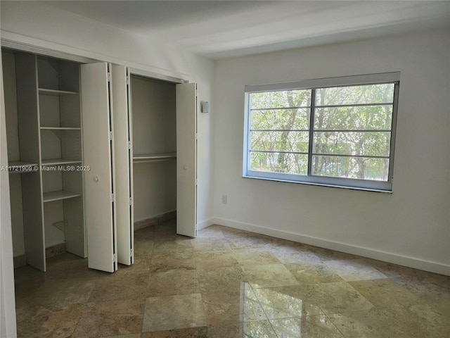 unfurnished bedroom featuring baseboards, stone finish floor, and a closet